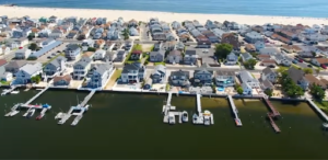 Aerial view of luxury waterfront homes with private boat docks along a canal in Point Pleasant Beach, NJ, showcasing premier Jersey Shore real estate near the Manasquan Inlet.