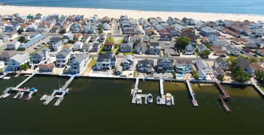 Aerial view of luxury waterfront homes with private boat docks along a canal in Point Pleasant Beach, NJ, showcasing premier Jersey Shore real estate near the Manasquan Inlet.